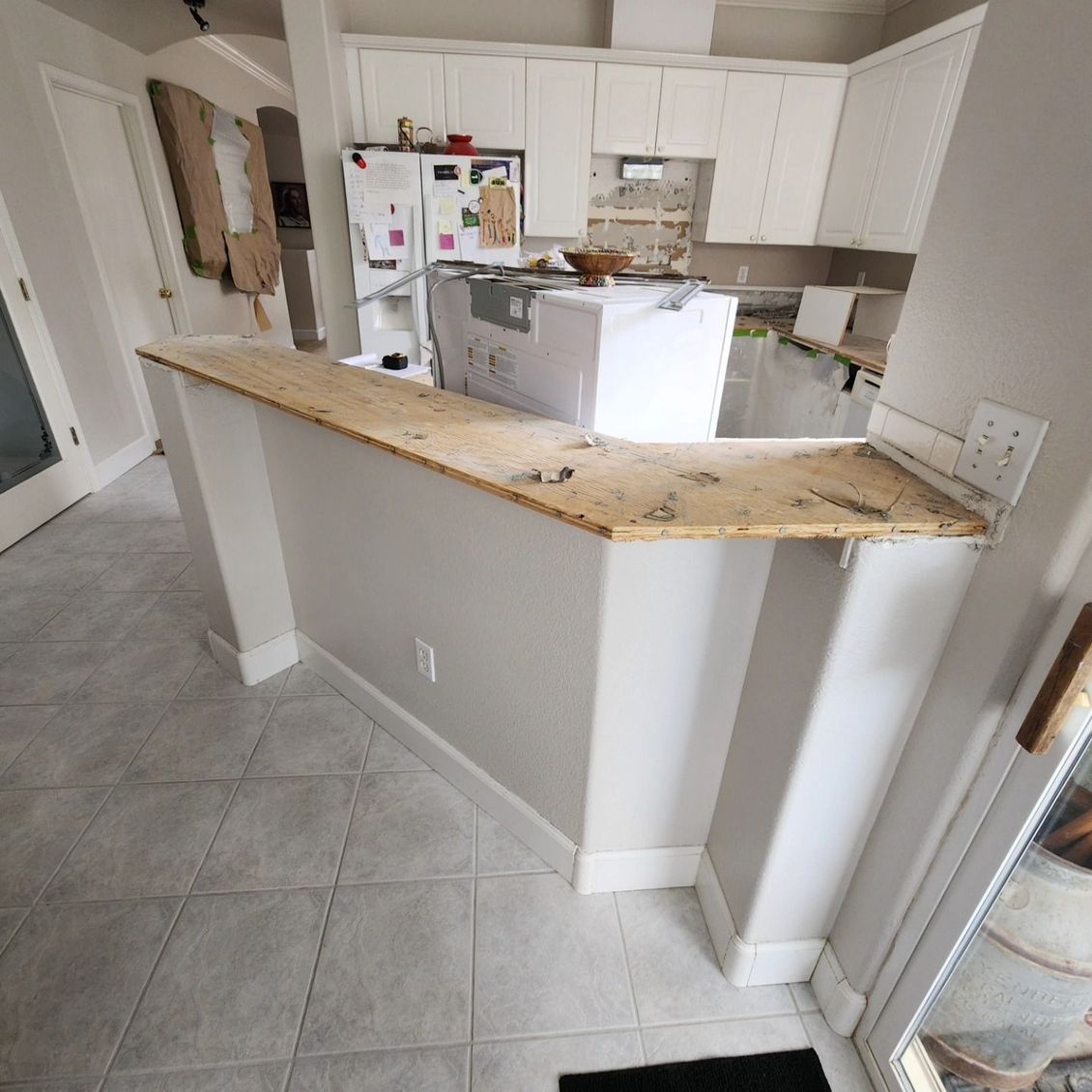 JJR Construction -  Kitchen island with a wooden countertop and cabinets, near a window and door.