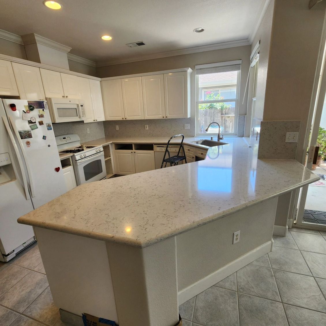 JJR Construction - Kitchen with white cabinets, light countertops, and a curved island.