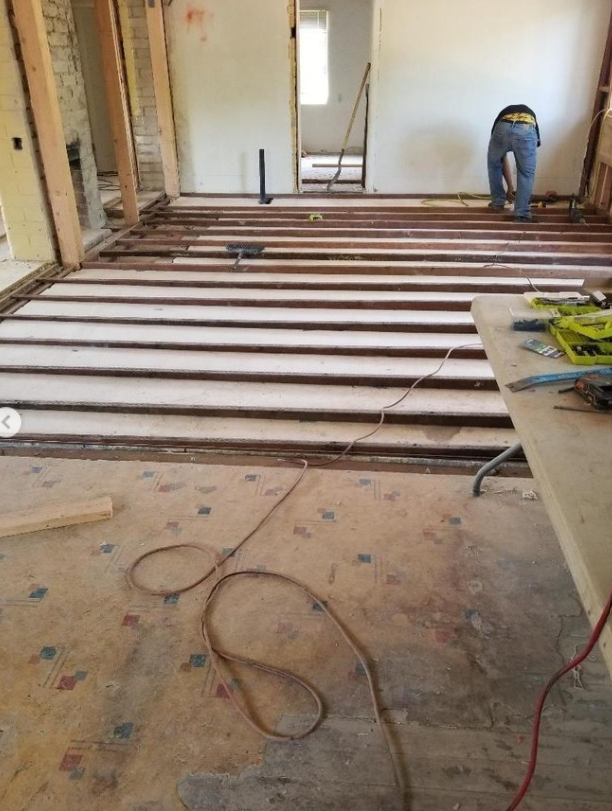 JJR Construction - Interior renovation with exposed floor joists, worker, tools, and wiring.