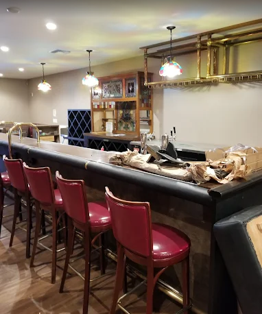 JJR Construction - A bar with red stools, liquor bottles, and light fixtures.