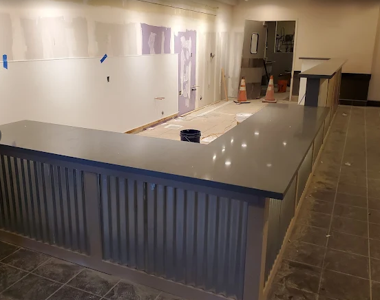 A gray bar with corrugated metal siding in an unfinished room with exposed walls.