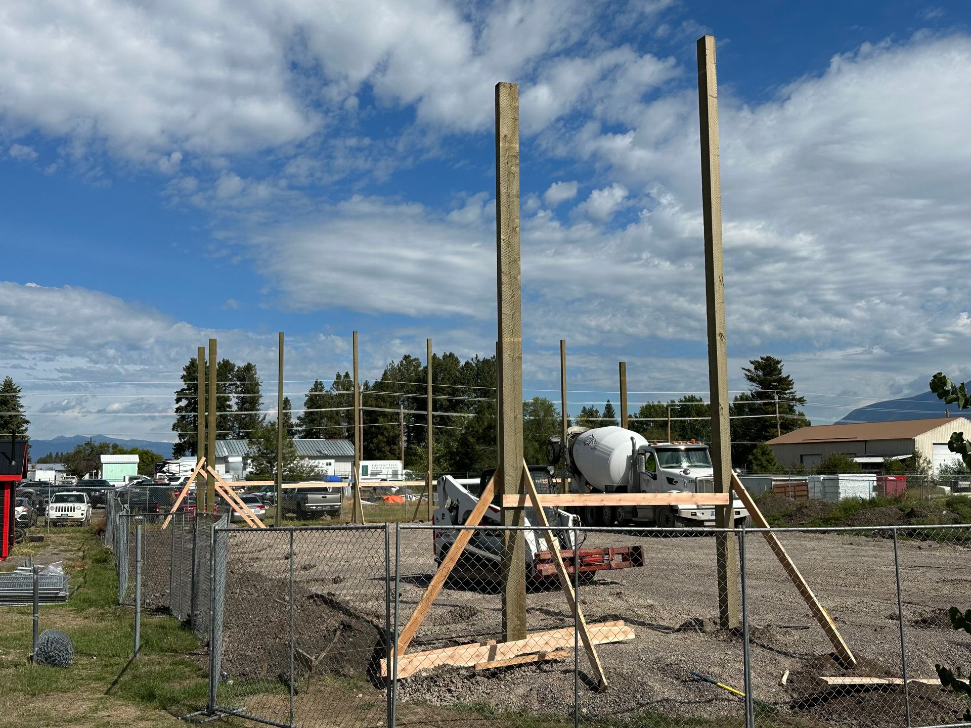 A construction site with a fence and a concrete mixer in the background.