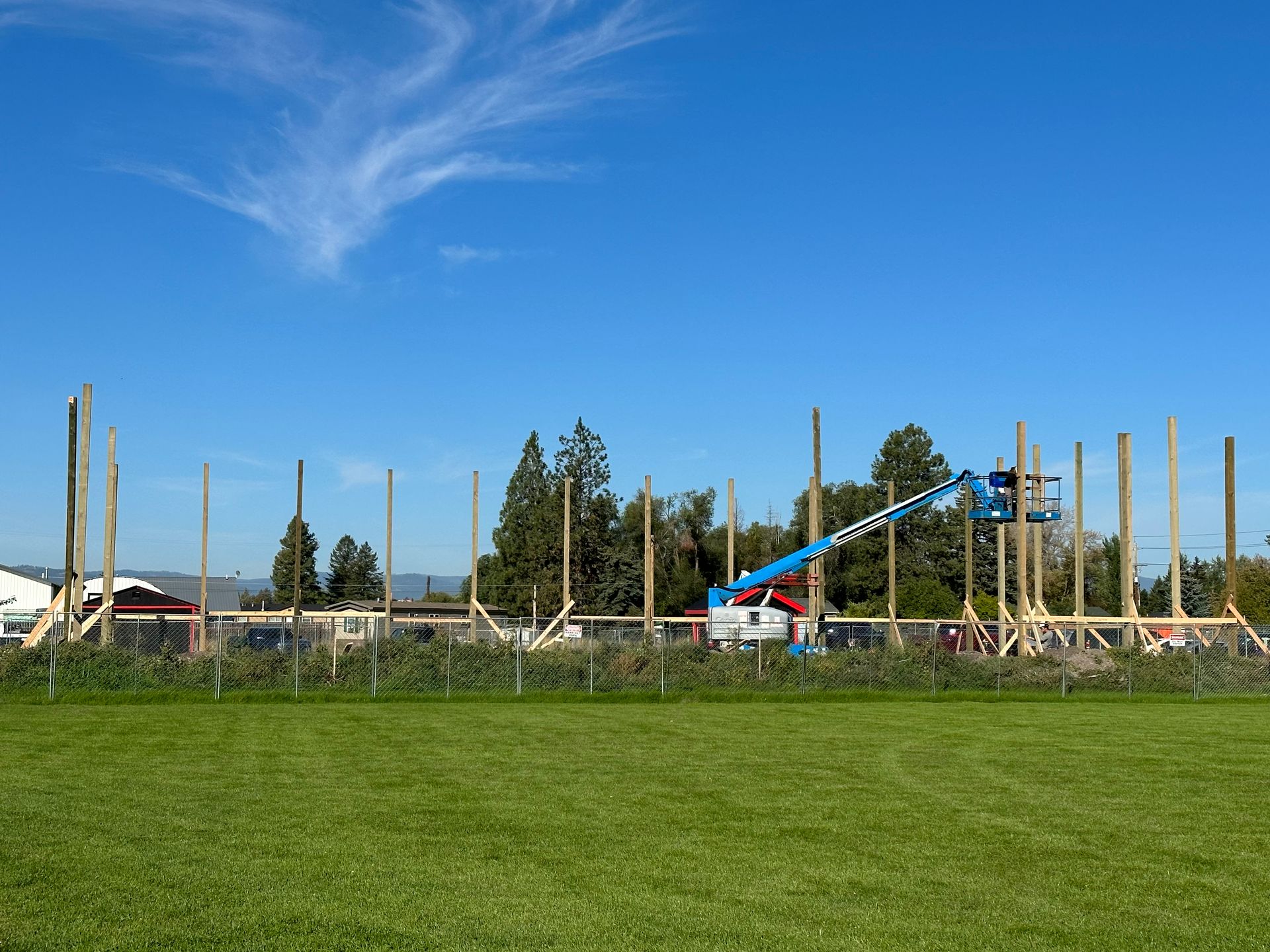 A large wooden structure is being built in a grassy field.