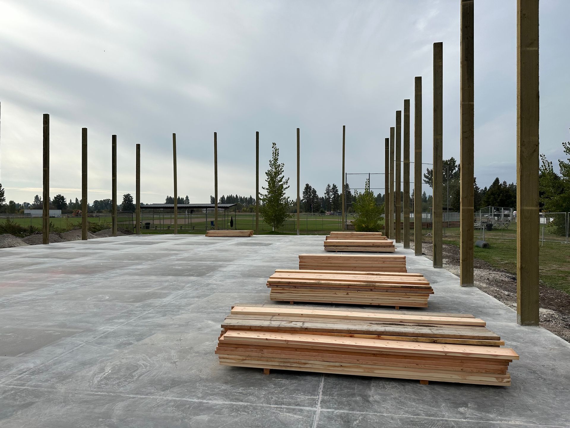A row of wooden posts are lined up on a concrete surface