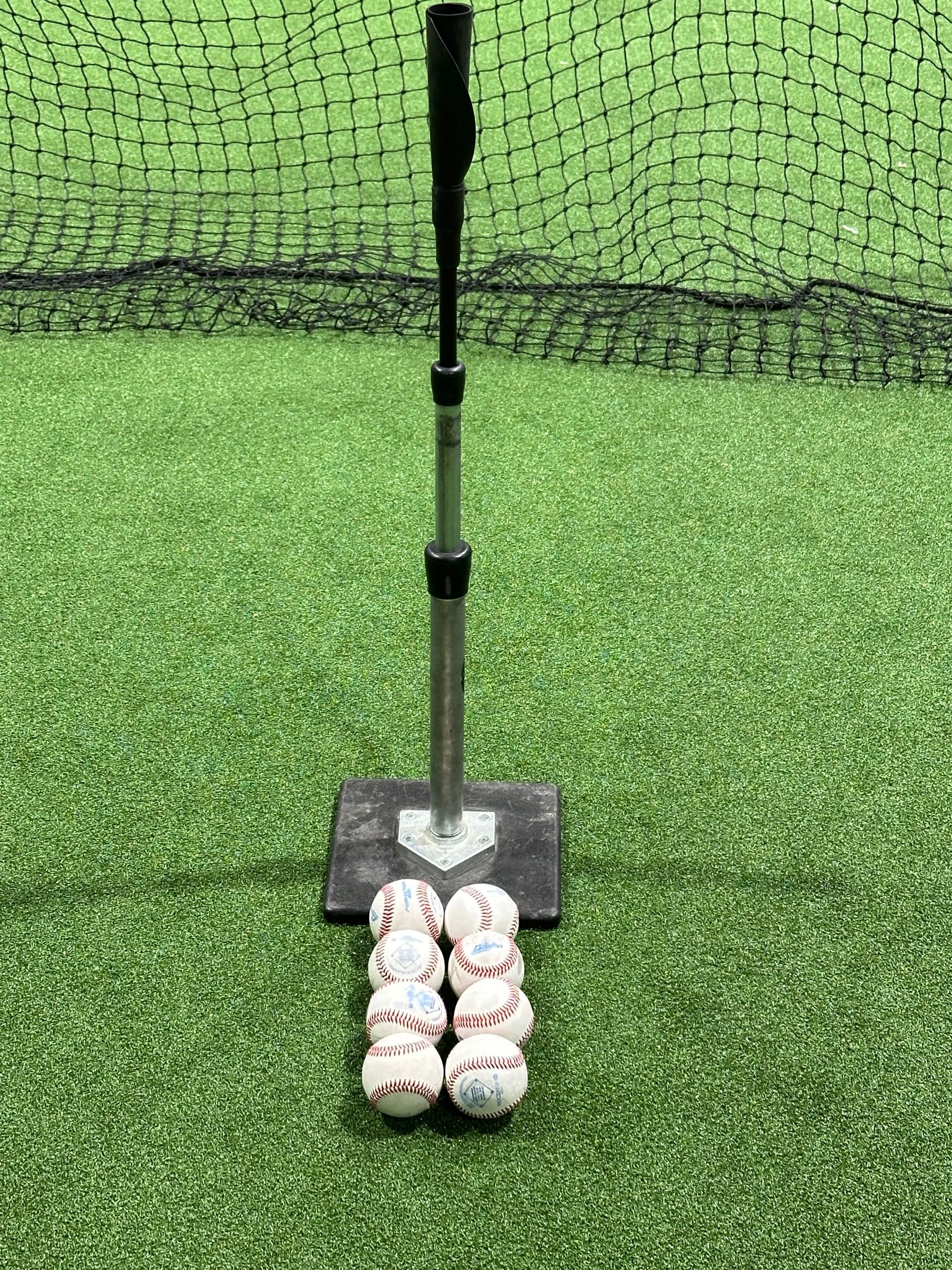 A tee with a bunch of baseballs on top of it.