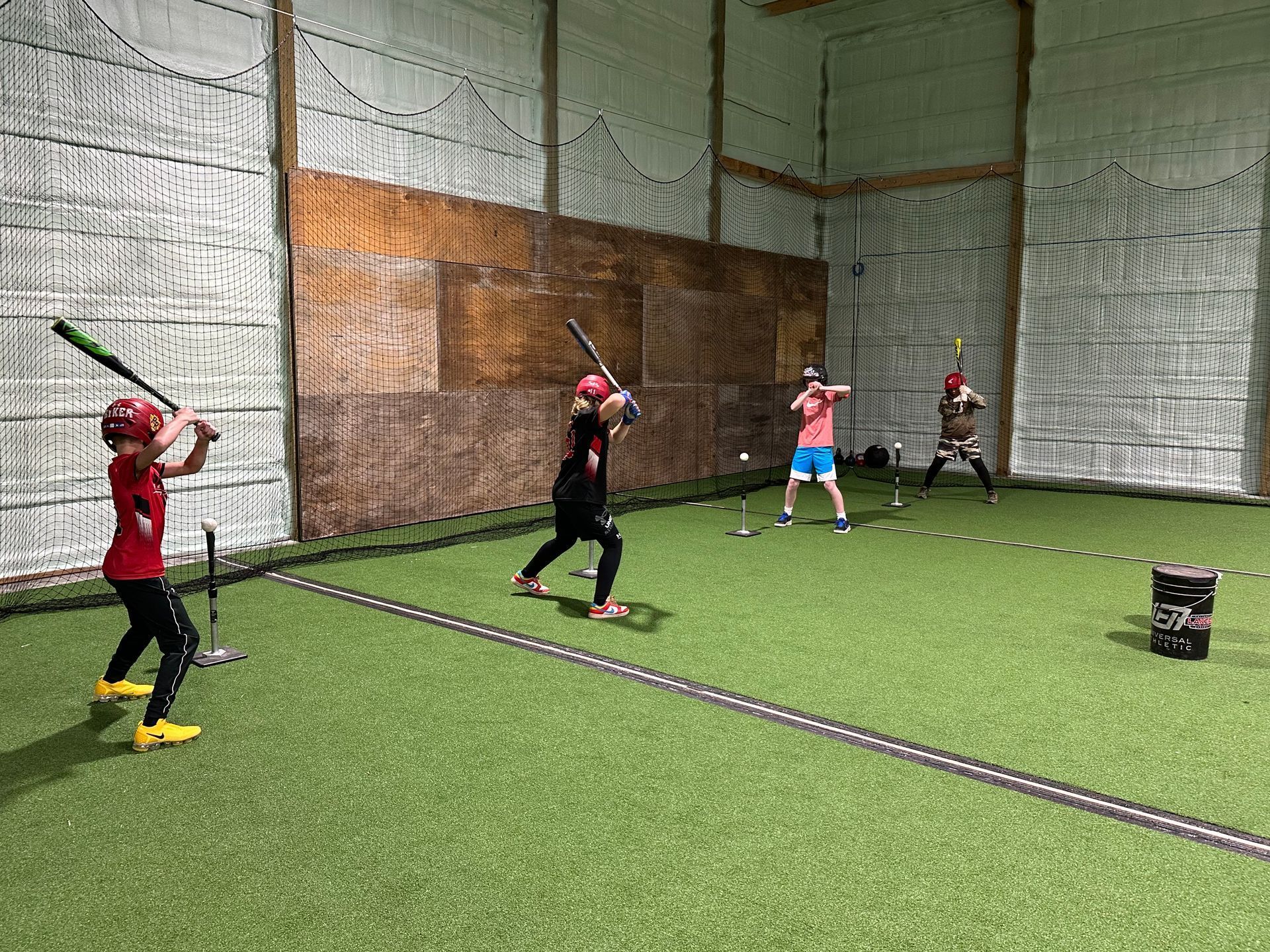 A group of children are playing baseball in an indoor stadium.