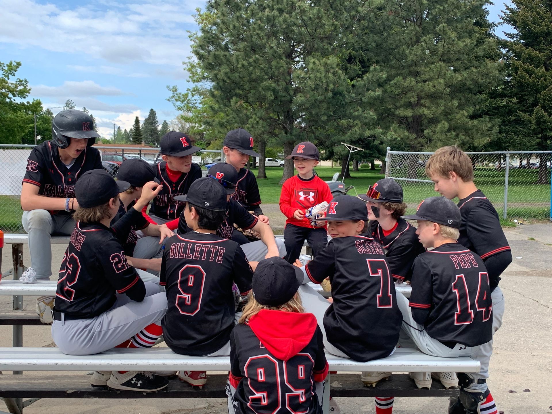 A group of young baseball players are sitting on a bench.