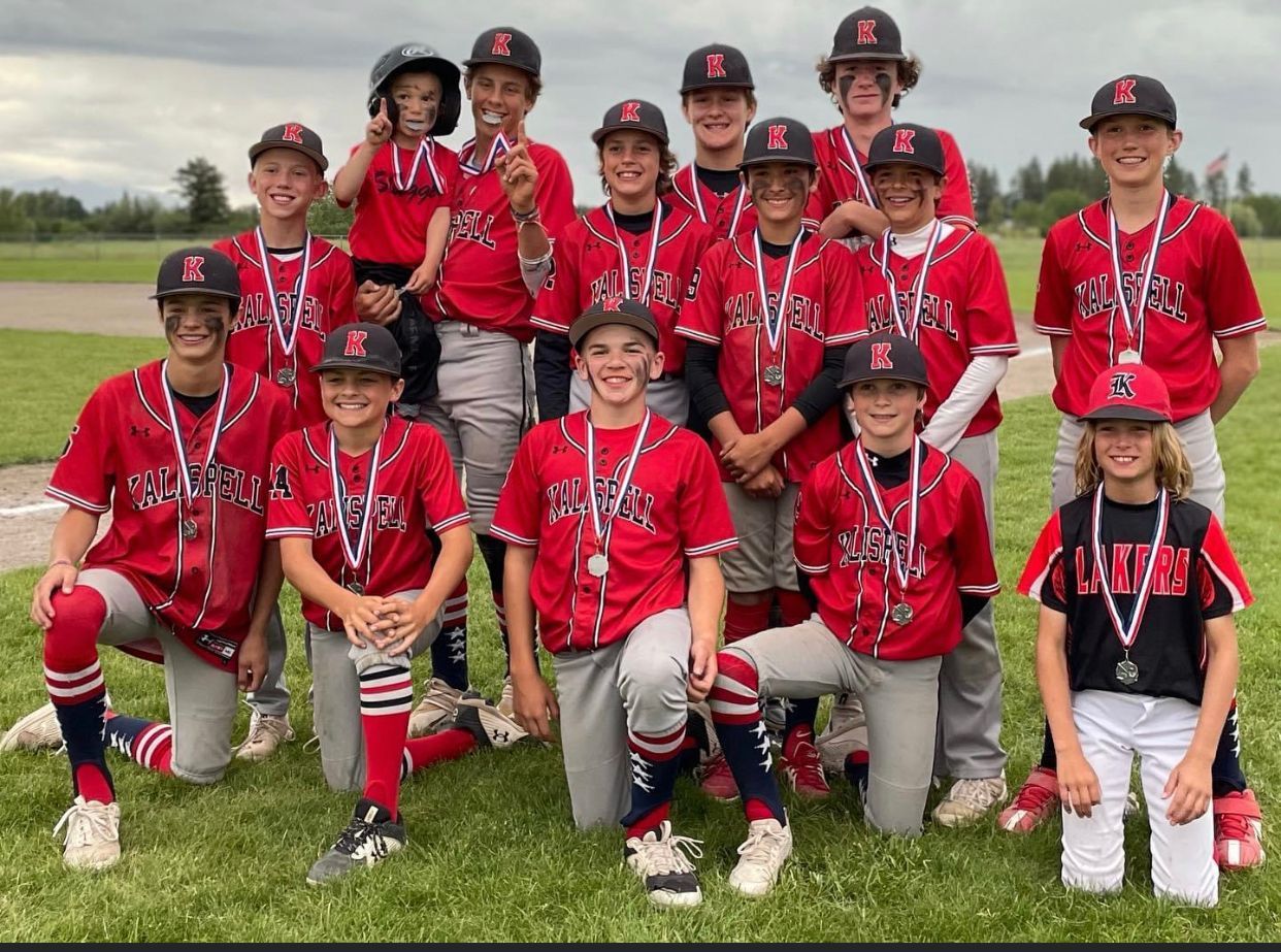 A group of young baseball players are posing for a picture on a field.