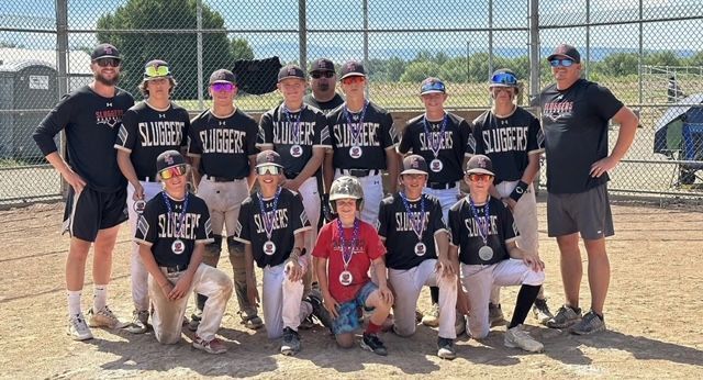 A group of young boys are posing for a picture on a baseball field.