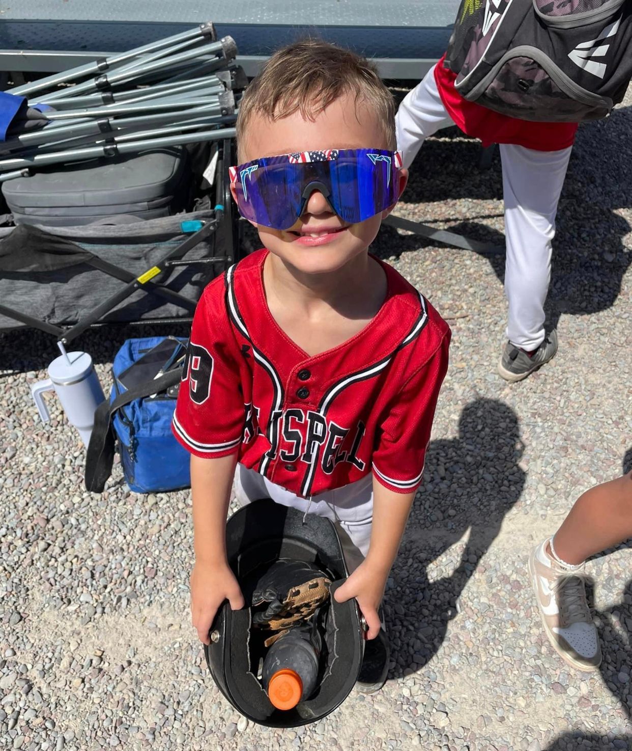 A young boy wearing sunglasses is holding a baseball glove.