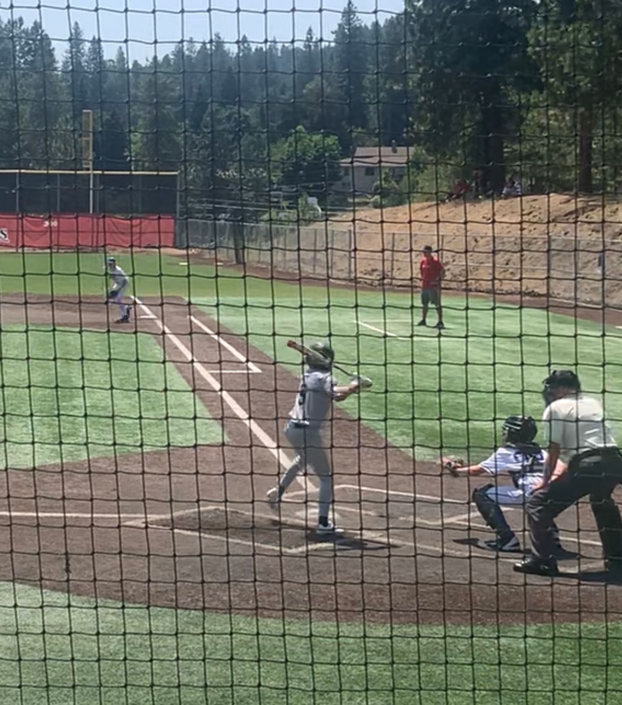 A baseball game is being played on a field behind a fence.