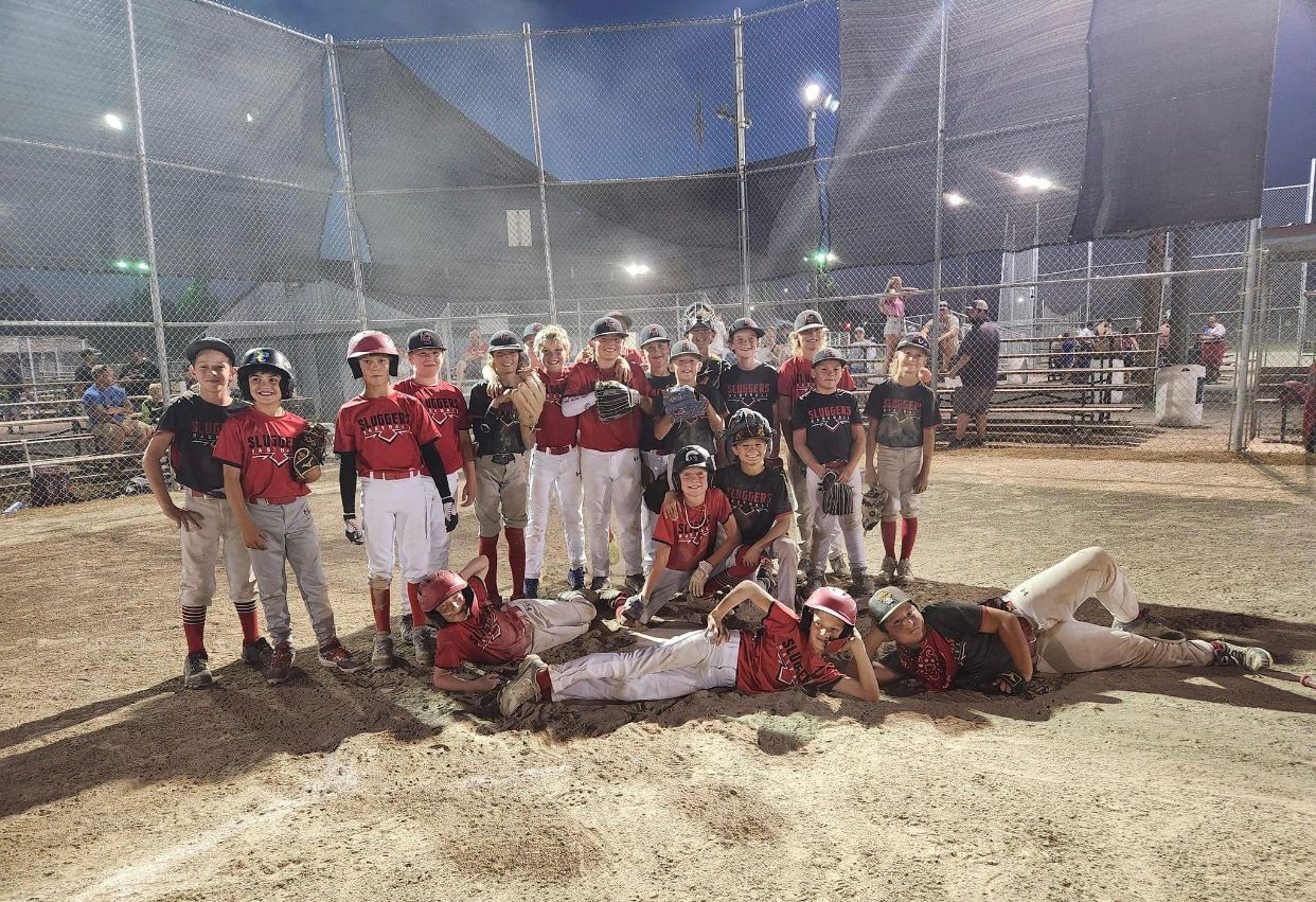 A group of young boys are posing for a picture on a baseball field.