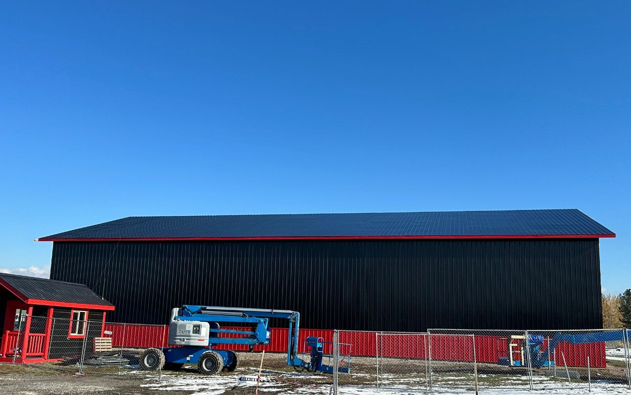 A large black building with a red trim is being built.