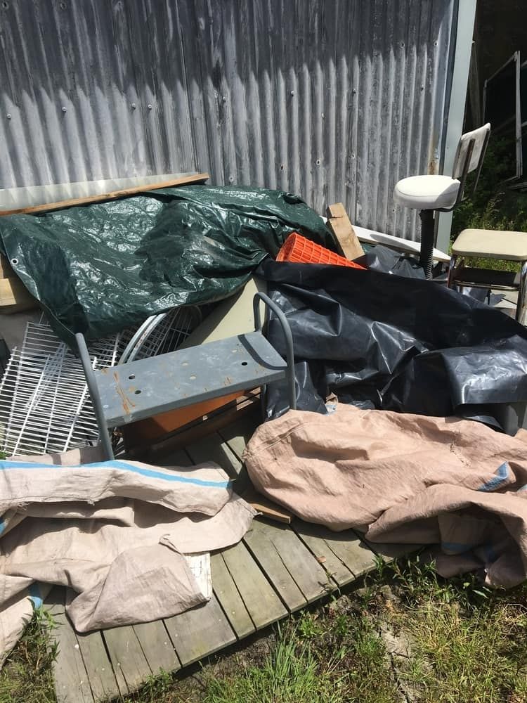 A Pile of Trash is Sitting on a Wooden Deck in Front of a Shed — Regina's Cleaning Group Pty Ltd In Lee Point, NT
