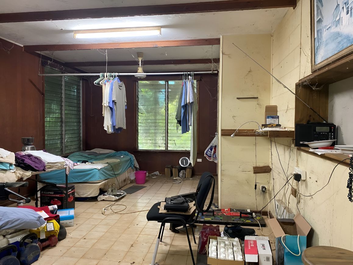 A Room With A Lot Of Clothes Hanging From The Ceiling And A Bed — Regina's Cleaning Group Pty Ltd In Lee Point, NT