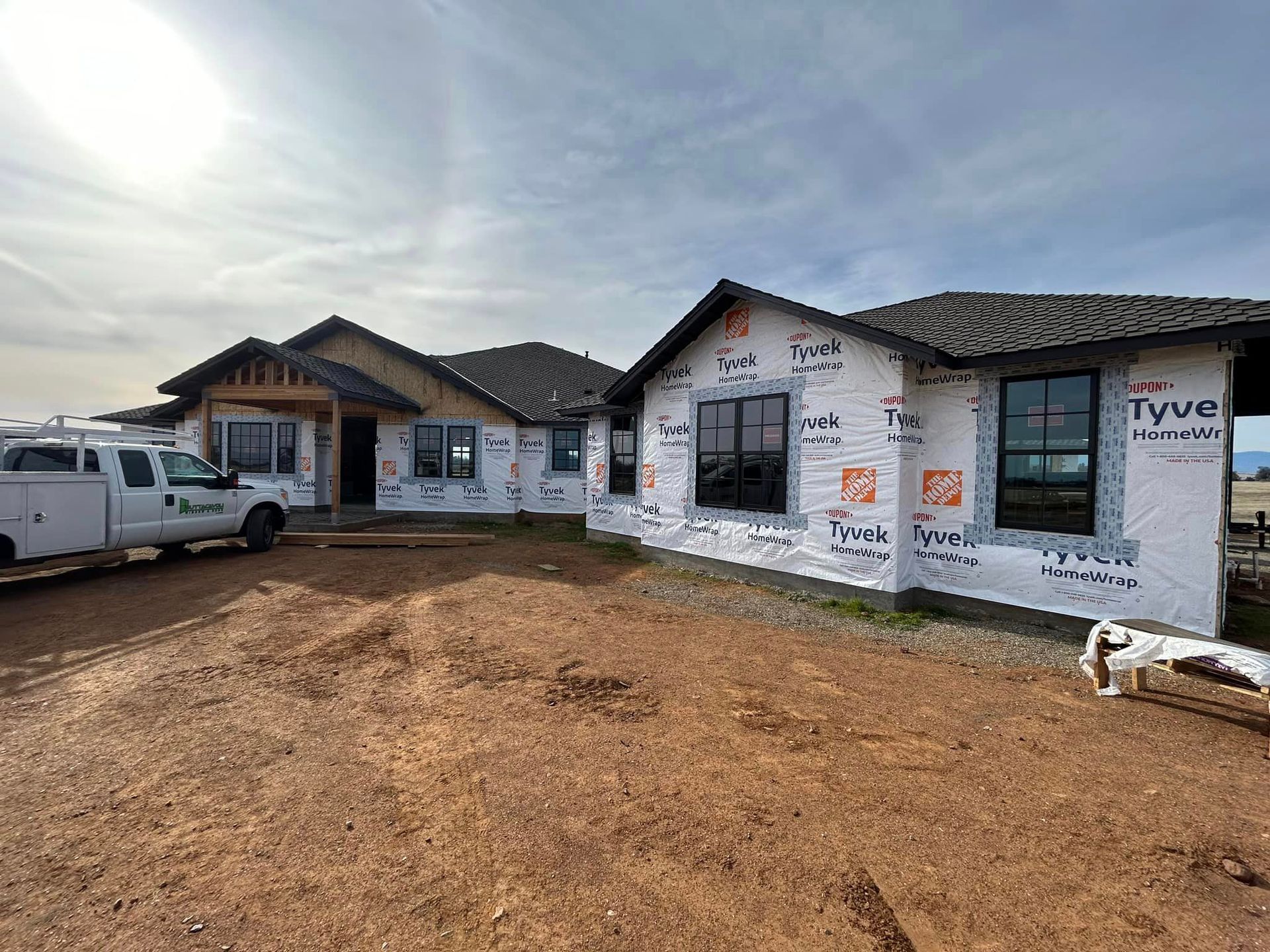 A white truck is parked in front of a house under construction with new windows