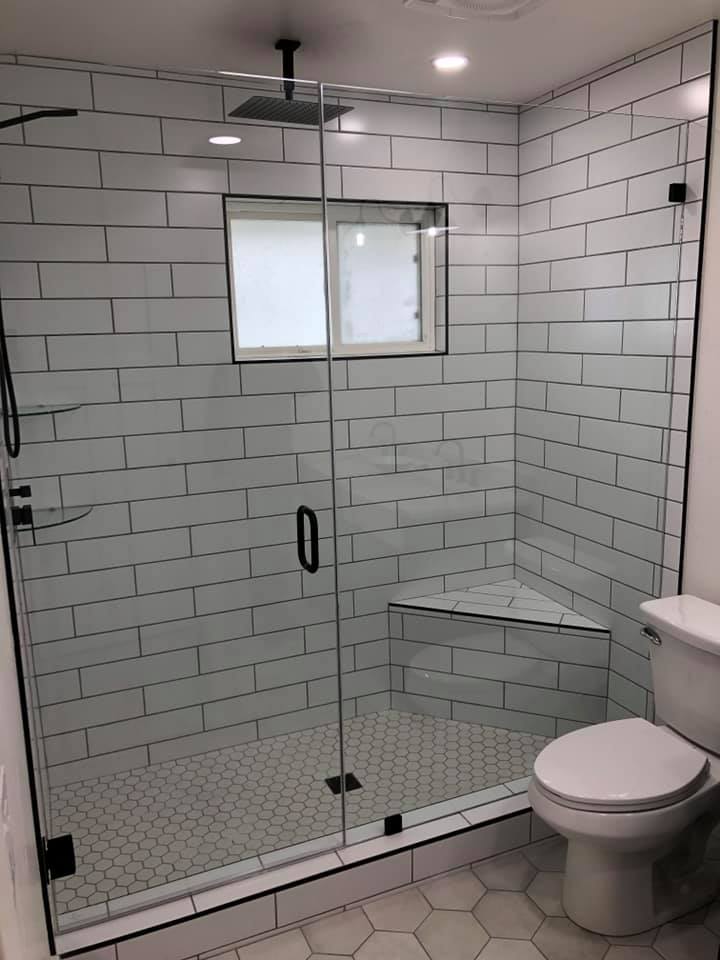 A bathroom with a walk in shower , toilet , and window.