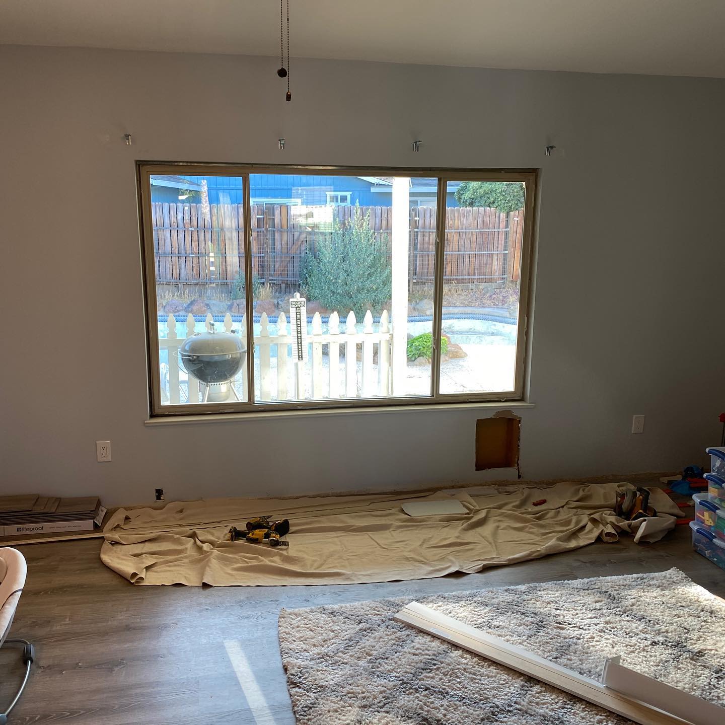 A living room with a large window and a rug on the floor.