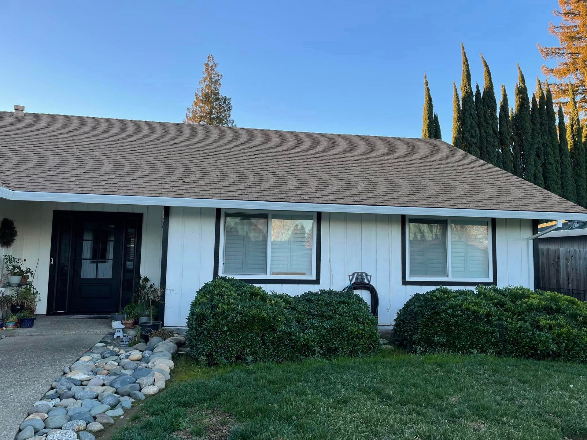 A white house with a brown roof and a black door.