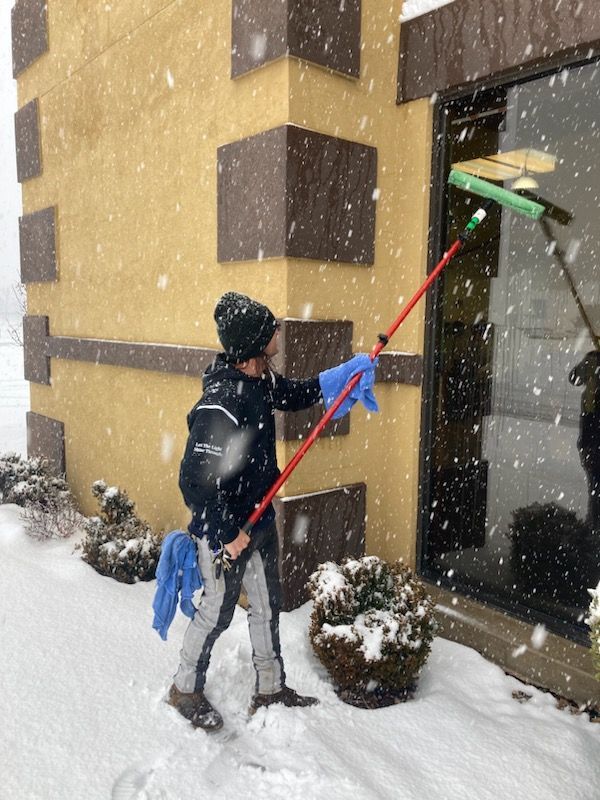 A man cleaning a window with a pole in the snow