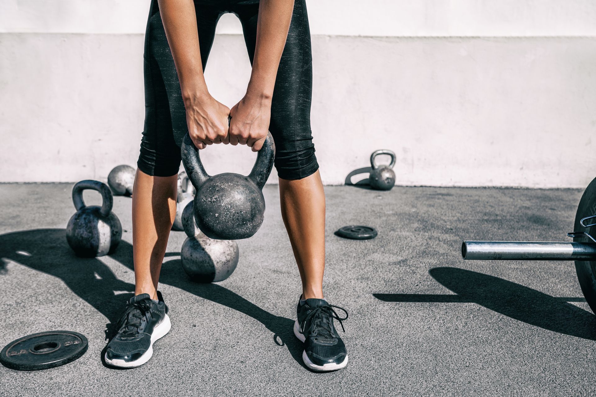 A woman is lifting a kettlebell in a gym.