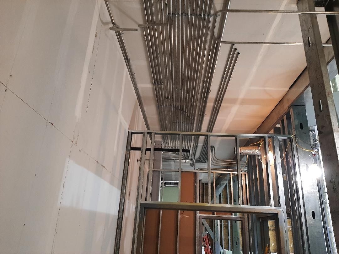 Interior view of unfinished construction; metal framing, conduit, and exposed drywall.