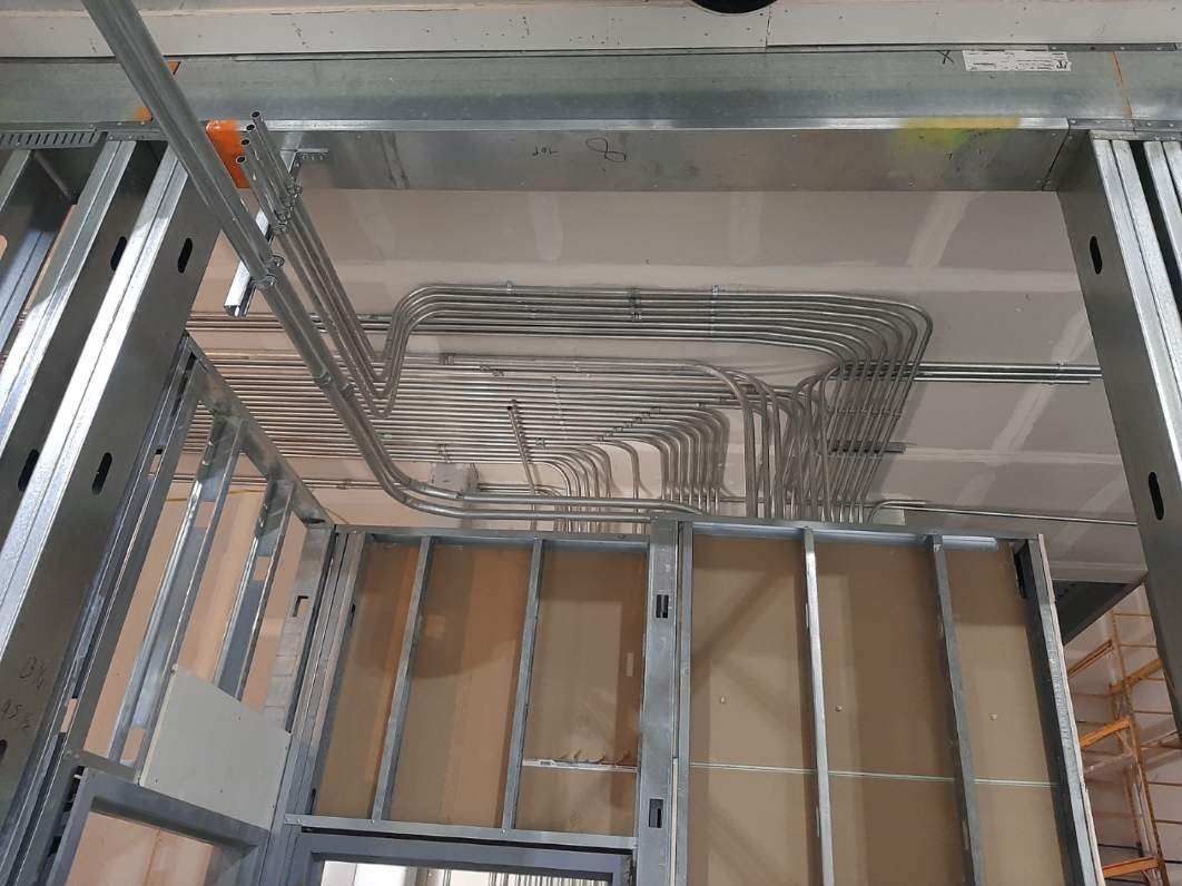 Metal framing and electrical conduits installed in a commercial building ceiling during construction.