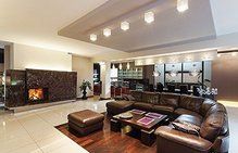 Upscale living room with a brown leather sectional, fireplace, and modern lighting.
