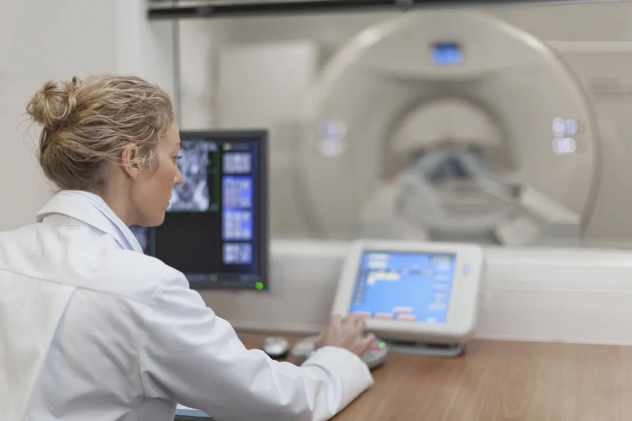 Doctor operating a control panel beside an MRI scanner