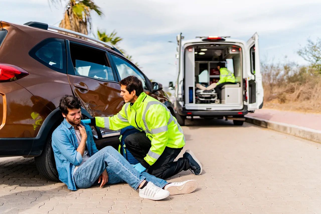 Car accident scene with a responder helping an injured person Car accident scene with a responder helping an injured person