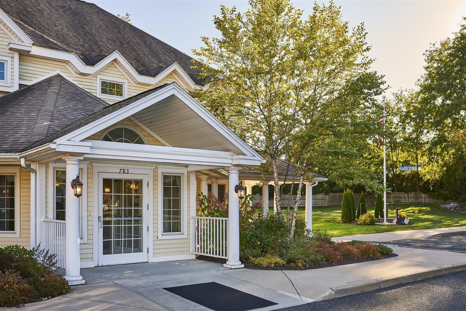 A large white house with a porch and trees in front of it.