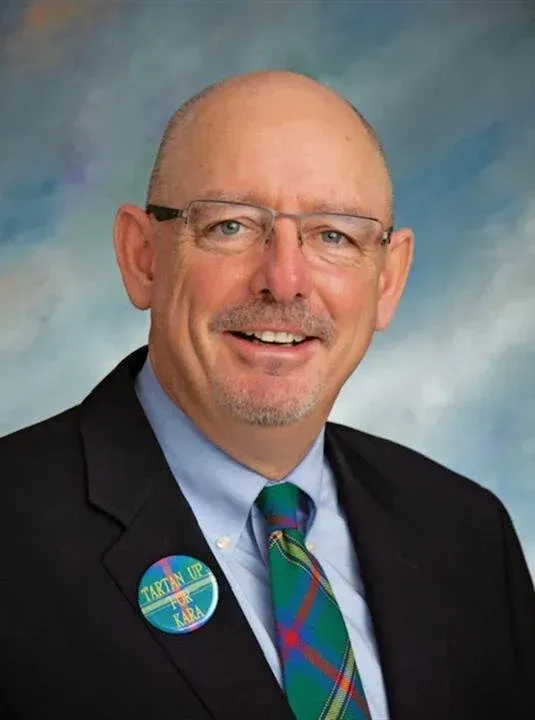 A man in a suit and tie has a button on his jacket that says 