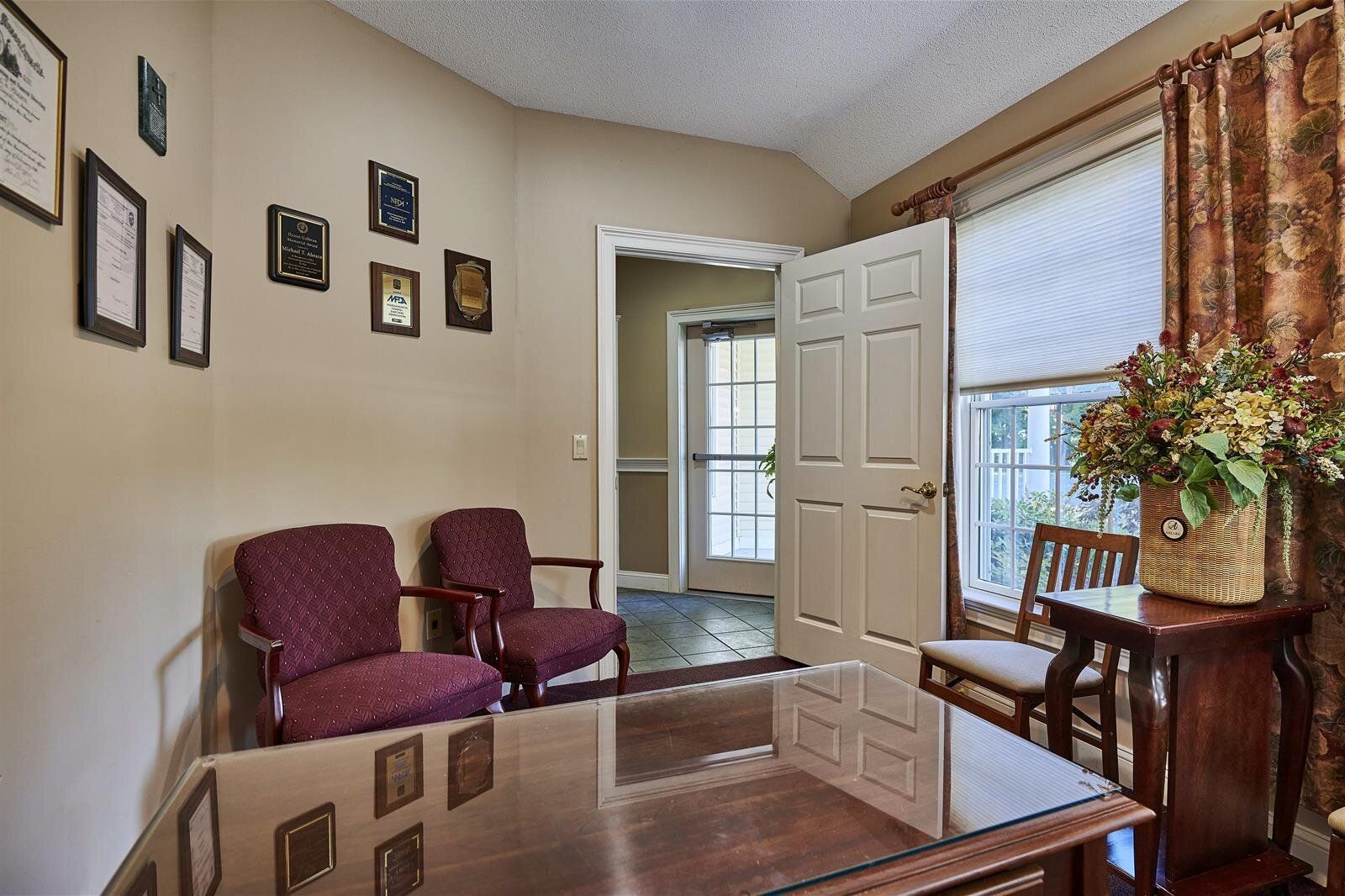 A waiting room with two chairs , a table , and a window.