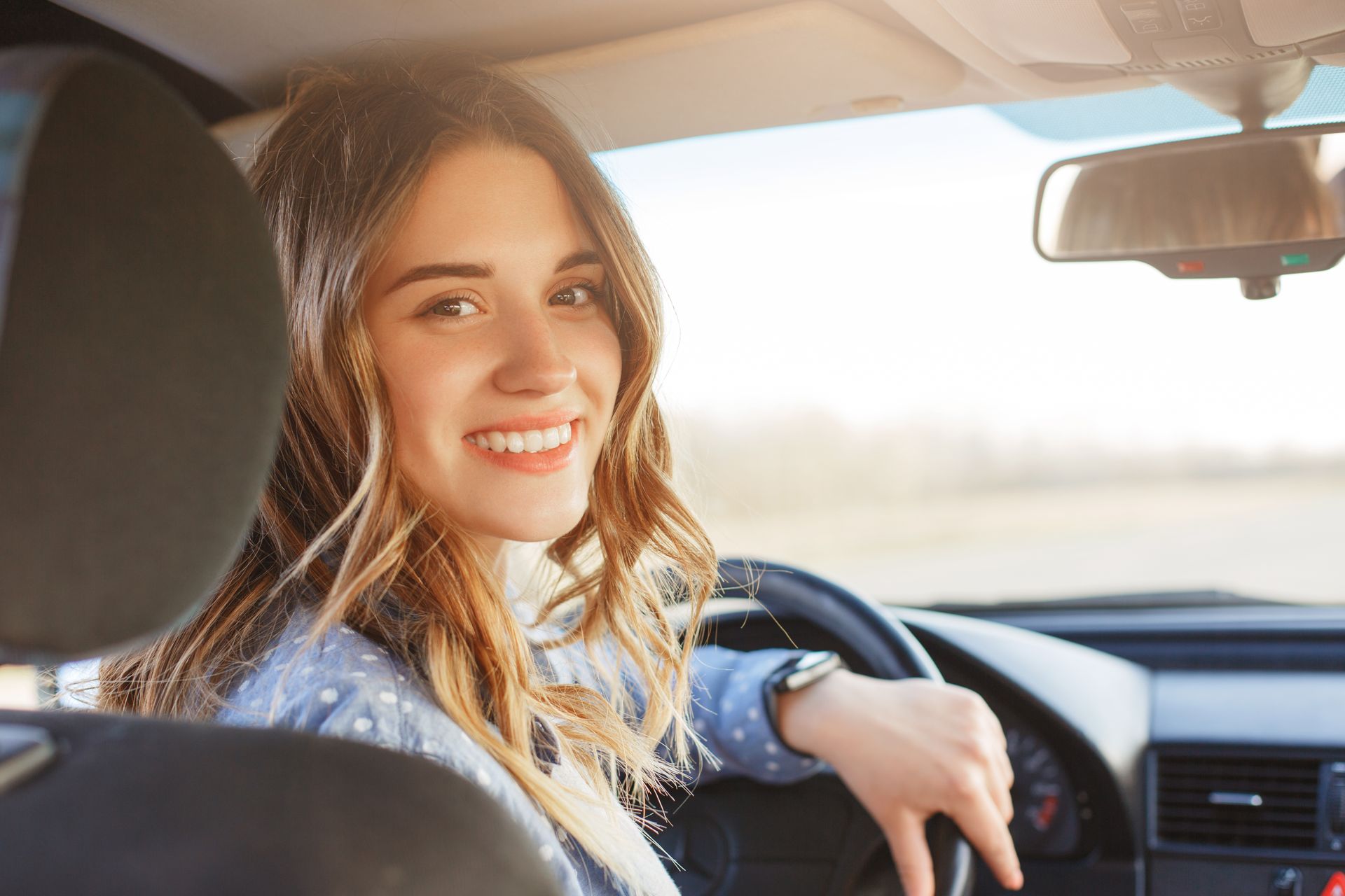 Woman smiling while driving a car.