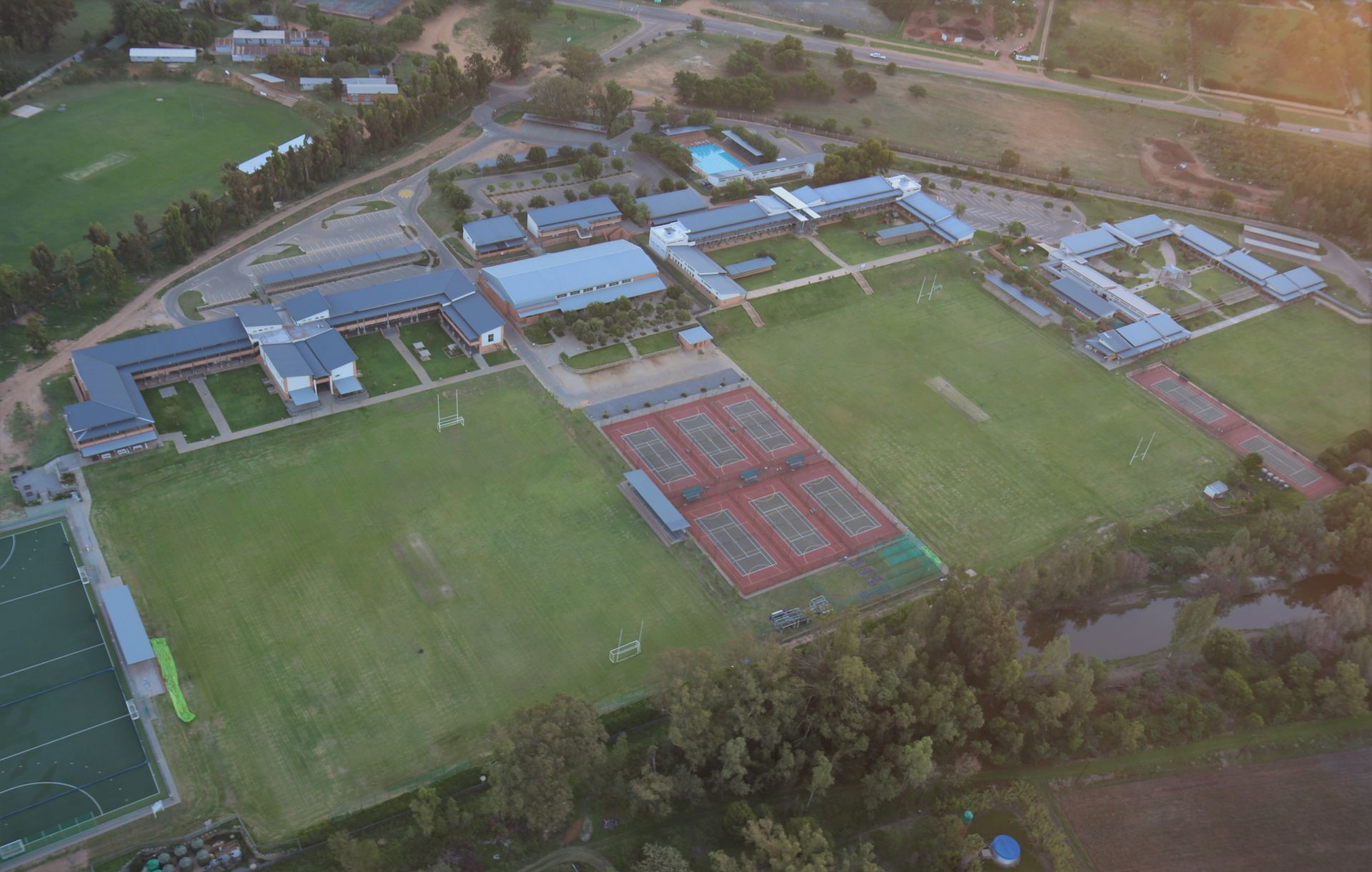 an aerial view of a school with a tennis court and a soccer field .
