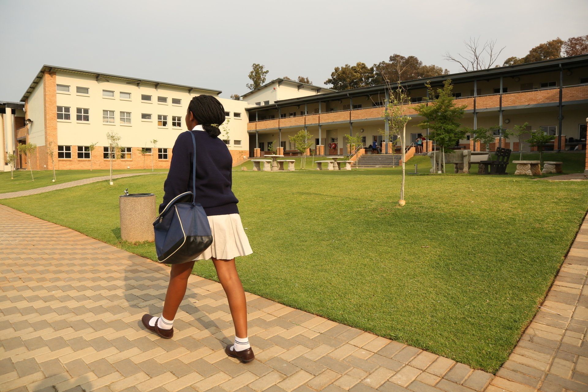 a girl is walking down a sidewalk in front of a school building .