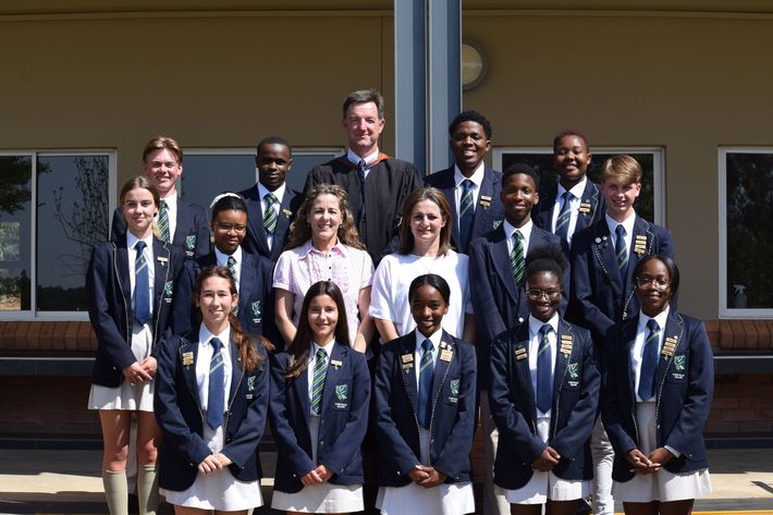 a group of students and teachers posing for a picture in front of a building