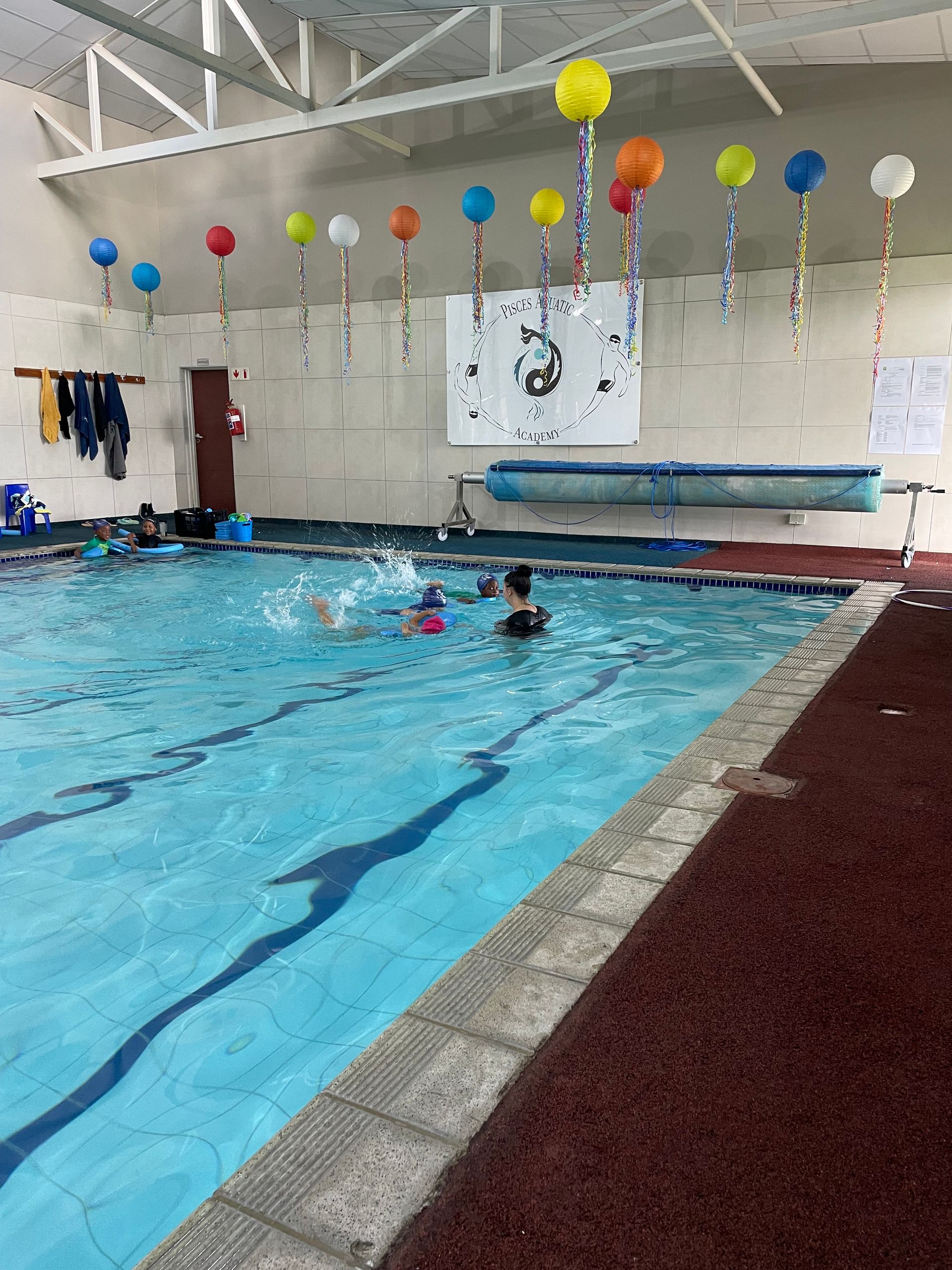 a swimming pool with balloons hanging from the ceiling
