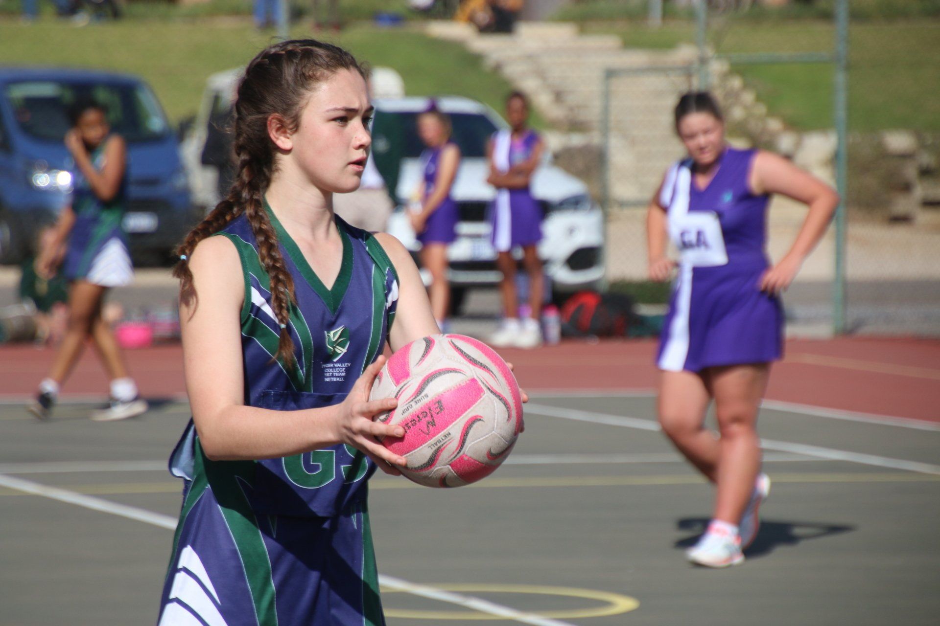 a girl in a basketball uniform is holding a ball on a court .