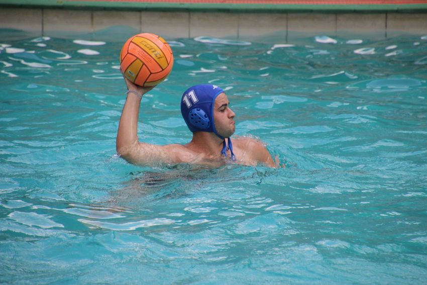 a boy is playing water polo in a swimming pool .