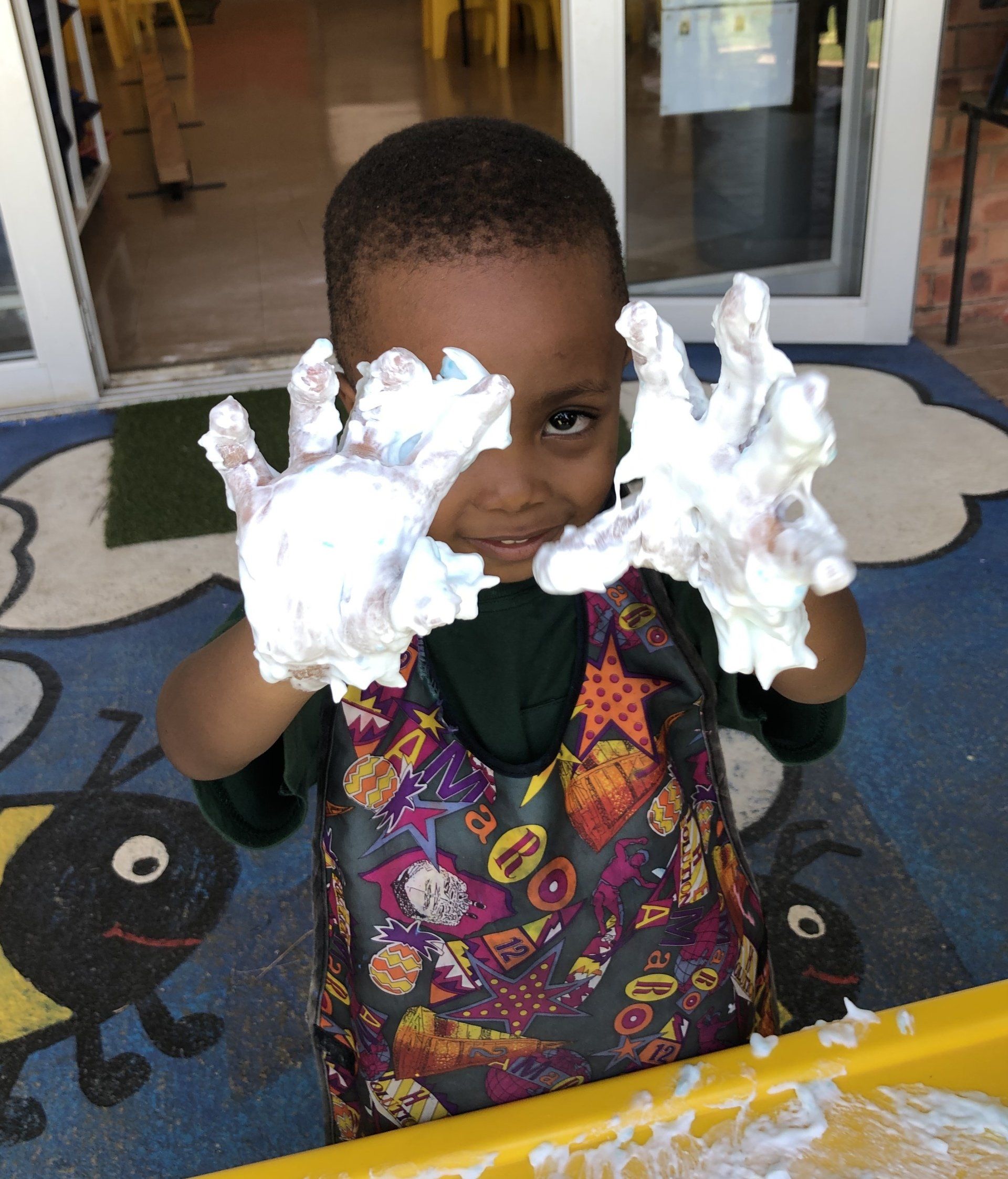 a young boy is playing with shaving cream on his hands