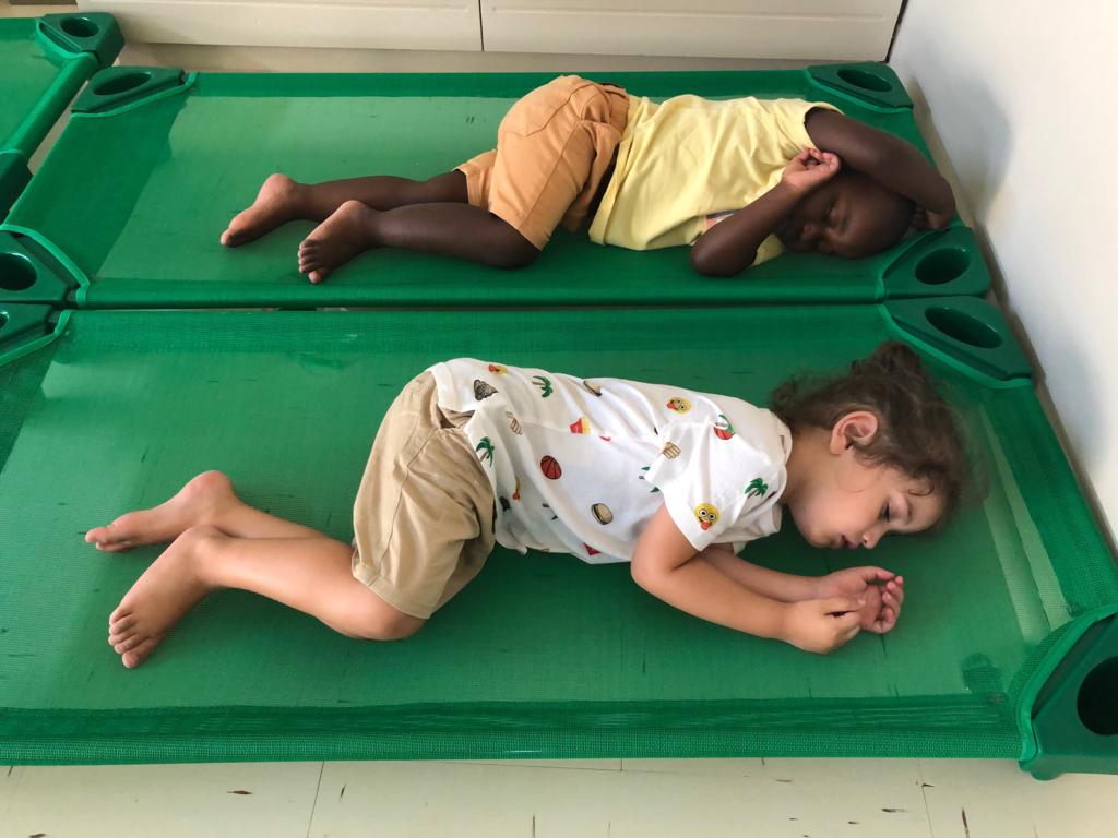 two children are sleeping on green beds in a room .