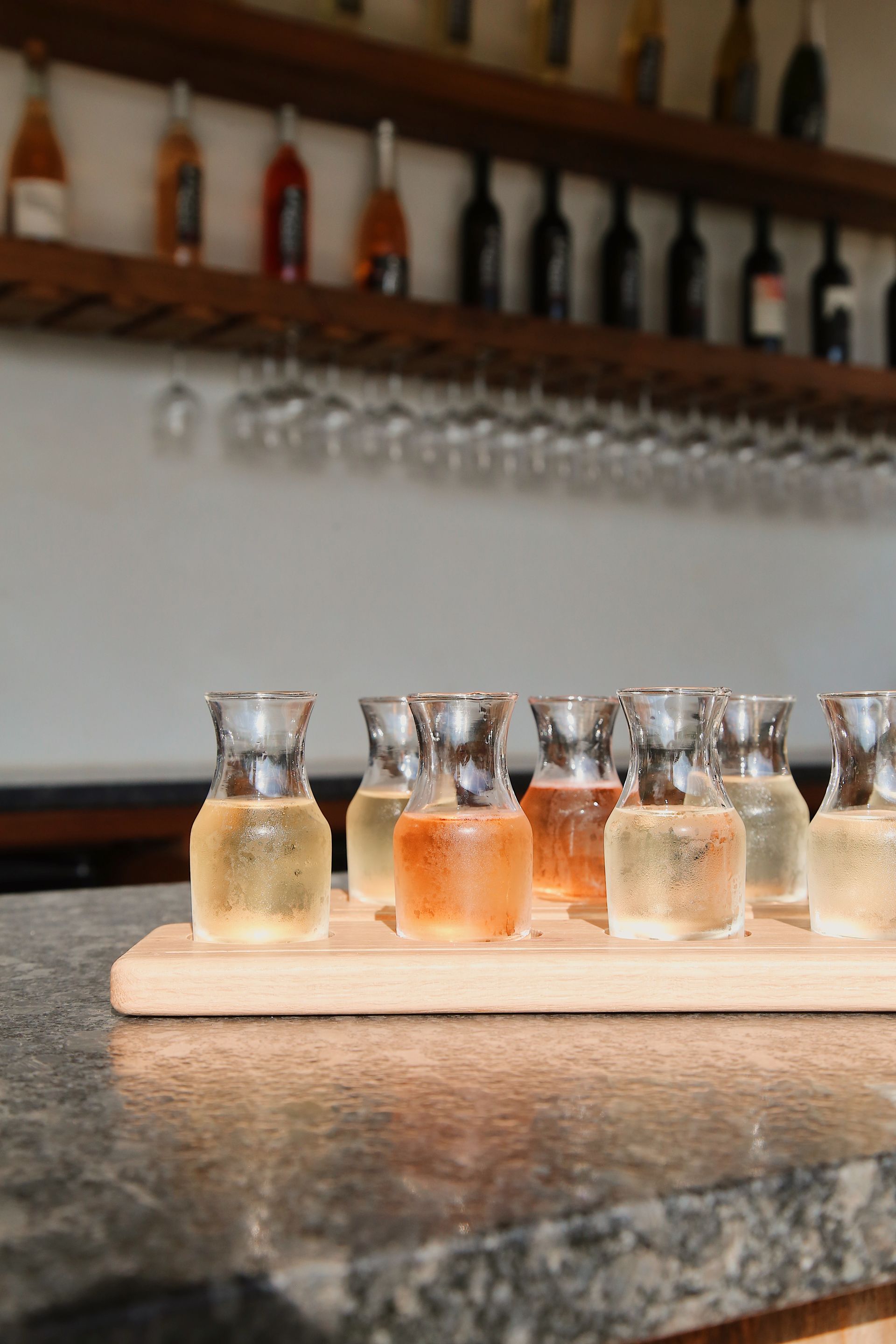 A wooden tray filled with small bottles of liquid on a counter.