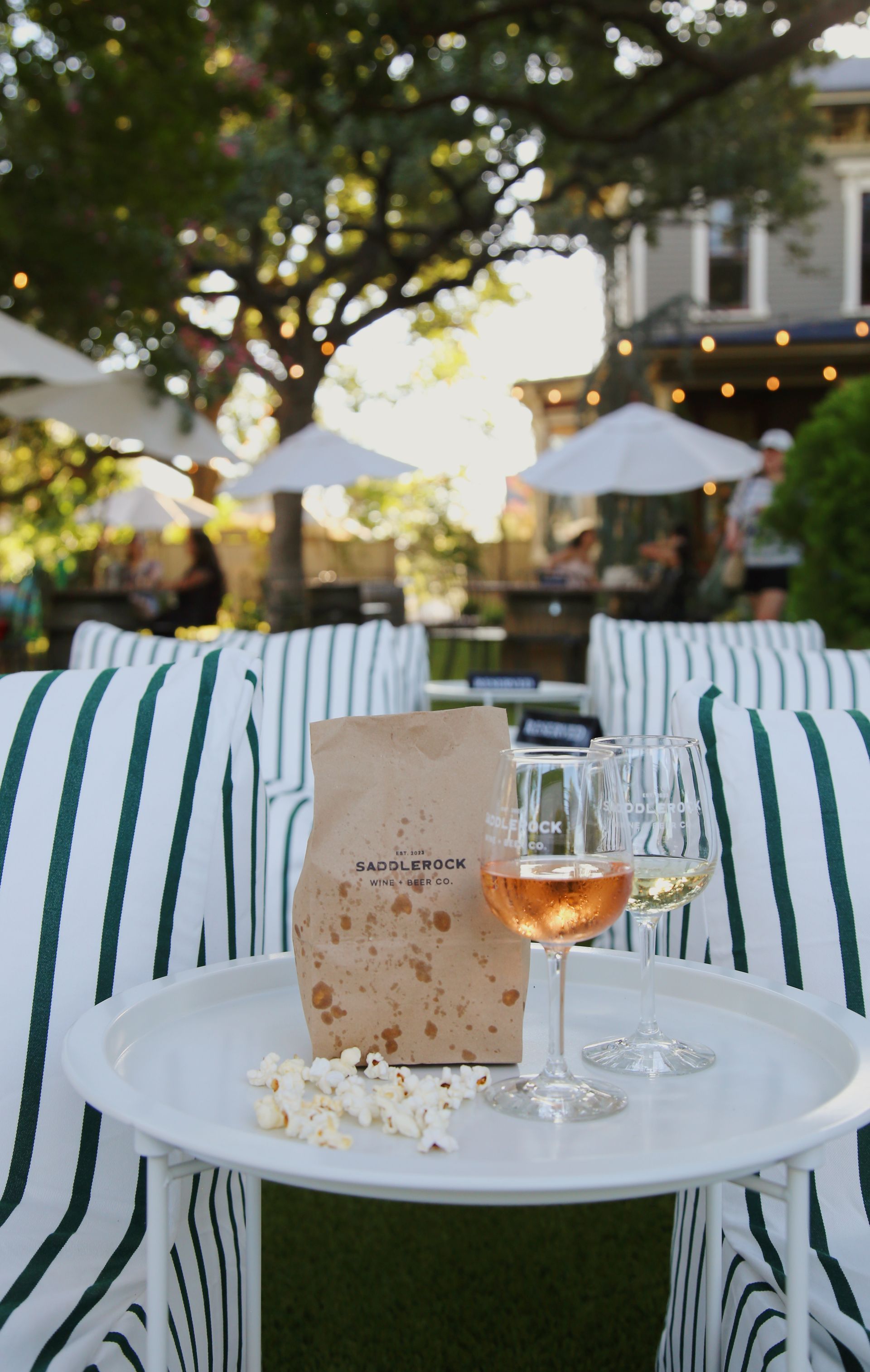 A table with a bag of popcorn and a glass of wine on it