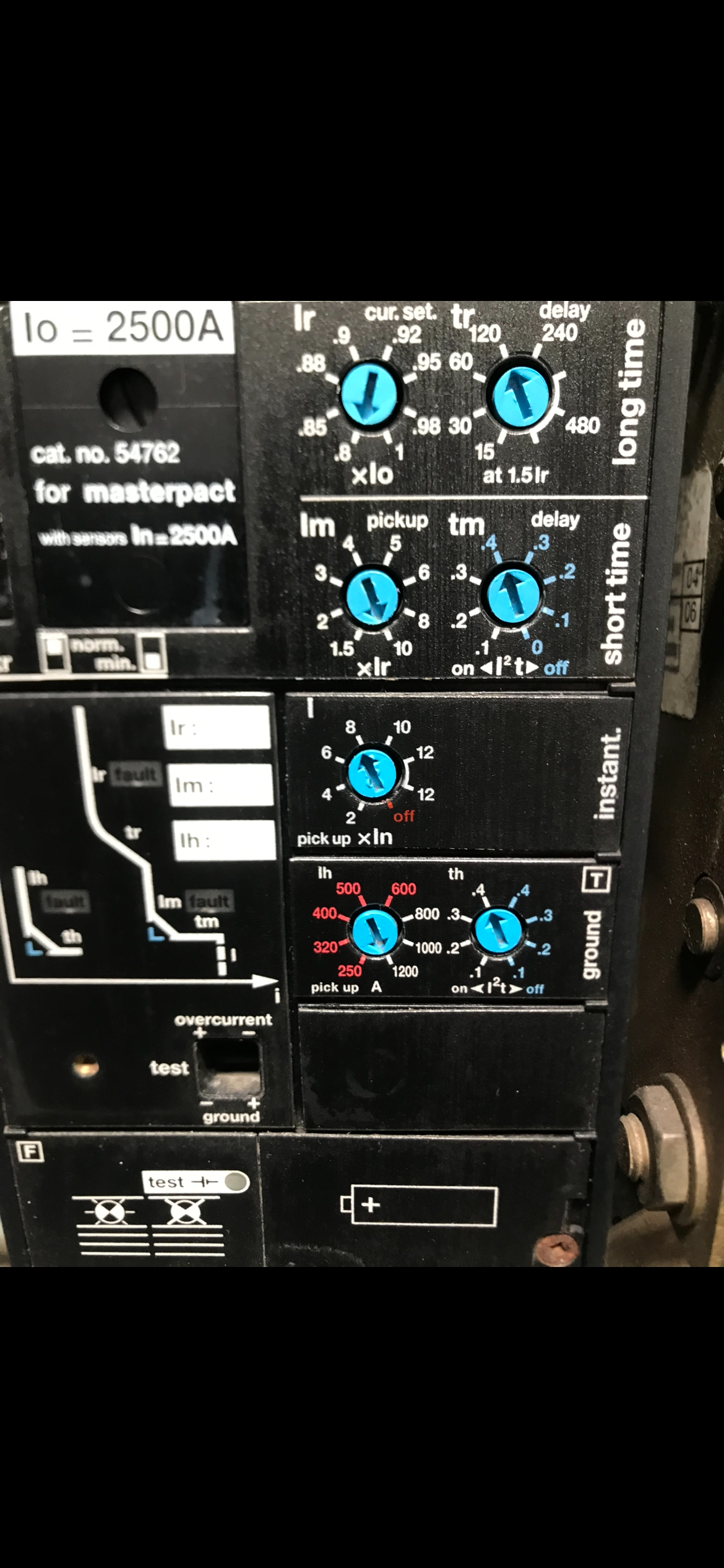 Control panel with knobs and dials for electrical equipment. Black background, blue dials.