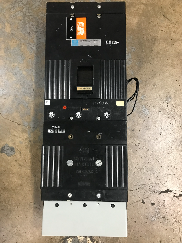 Black electrical circuit breaker on a cement floor.