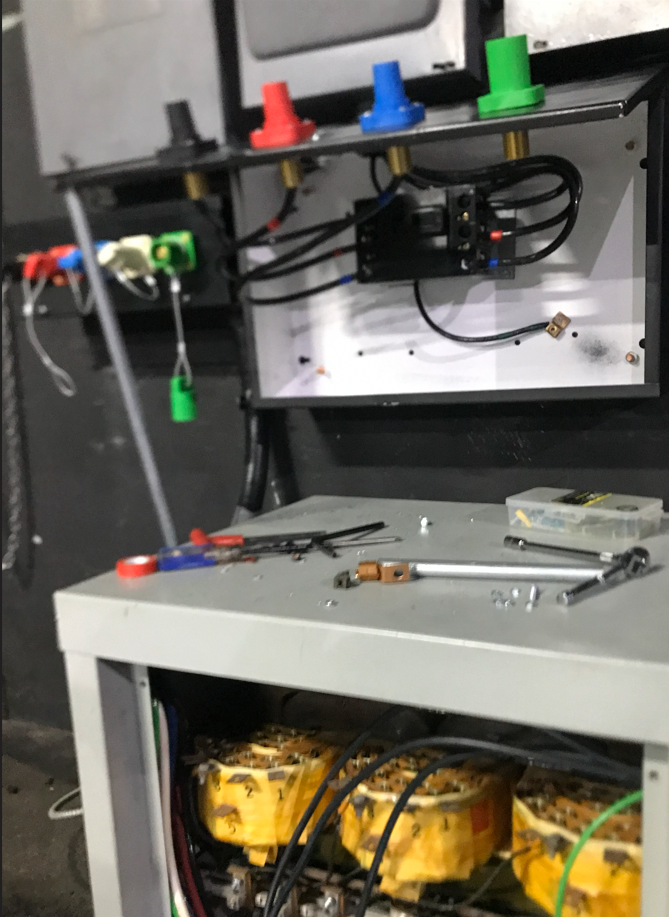 Electrical panel with colored plugs, wires, and tools on a work surface.