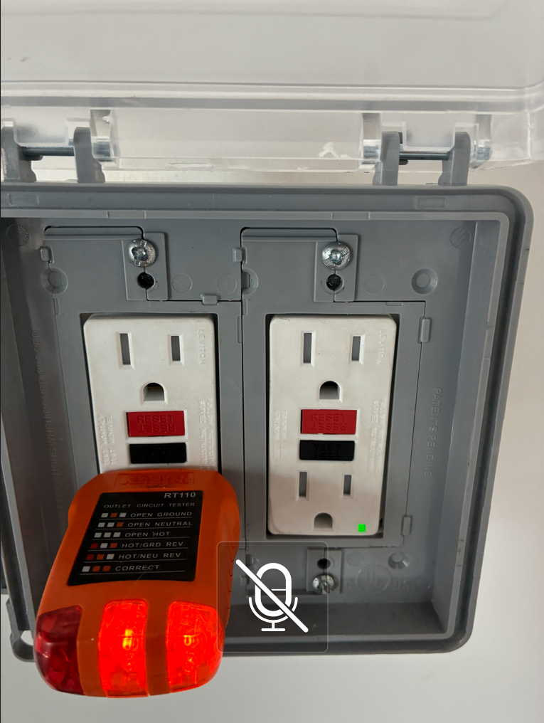 Electrical outlet tester showing incorrect wiring in an outdoor electrical box; red light indicates a fault.