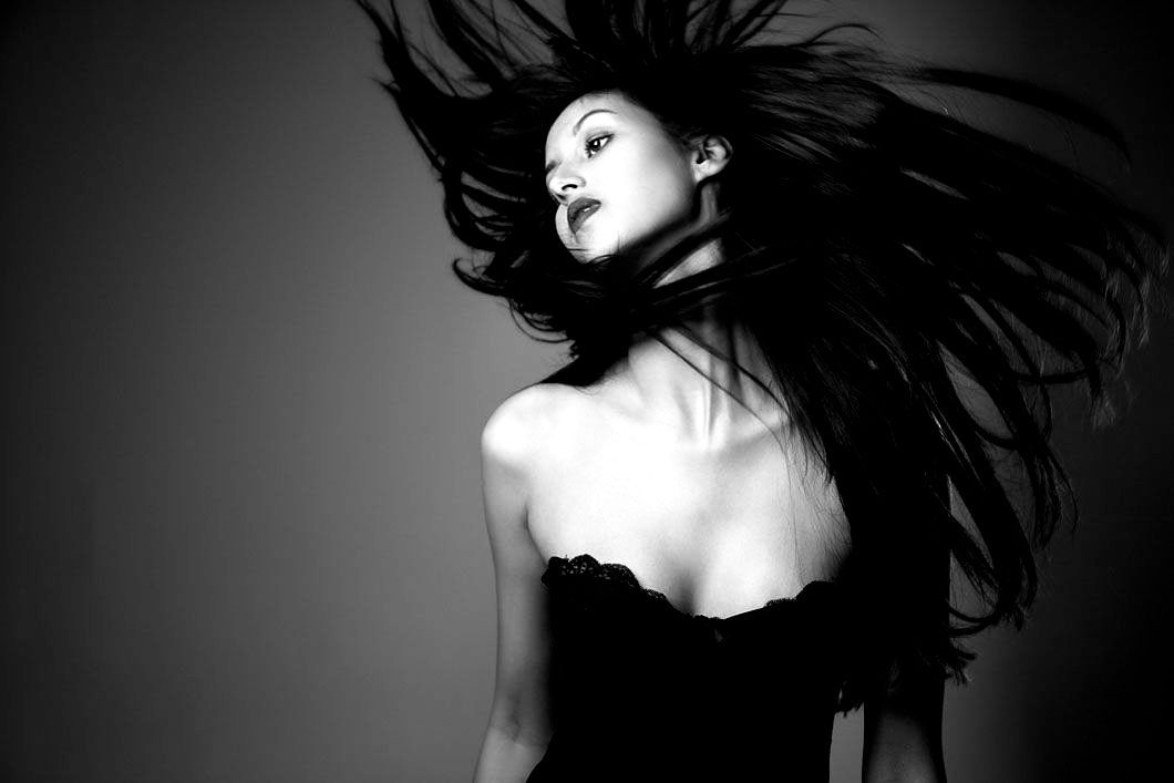 A black and white photo of a woman with her hair blowing in the wind.