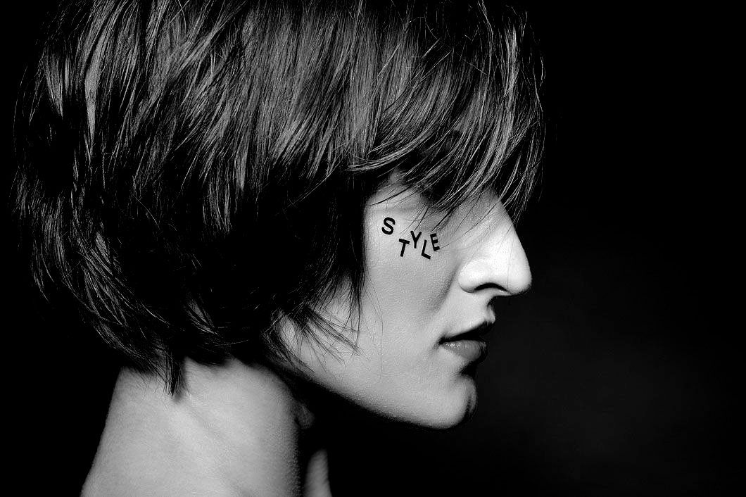 A black and white photo of a woman with a tattoo on her face.